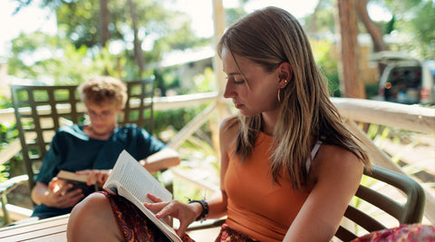 Dois adolescentes a ler um livro no alpendre