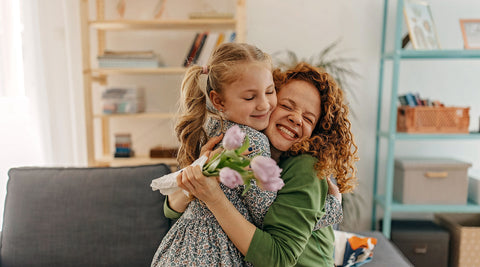 Mãe e filha abraçadas depois de receber flores como presente do dia da mãe 