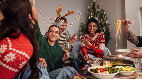 Jovens a celebrar um jantar de Natal, a conversar e a sorrir