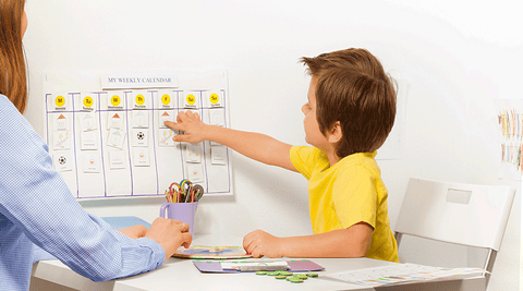 Criança a apontar para um horário escolar, acompanhada por um adulto num ambiente educativo, destacando a importância da organização e definição.