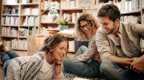 Grupo de jovens a conversar sobre livros numa biblioteca pública