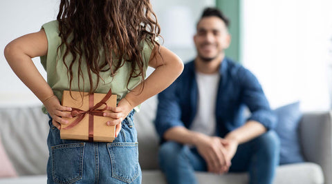 menina a surpreender o pai com presente escondido atrás das costas