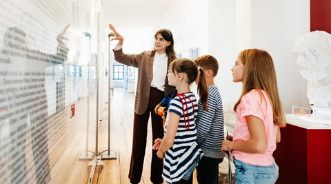 Guia a explicar exposição a grupo de crianças num museu