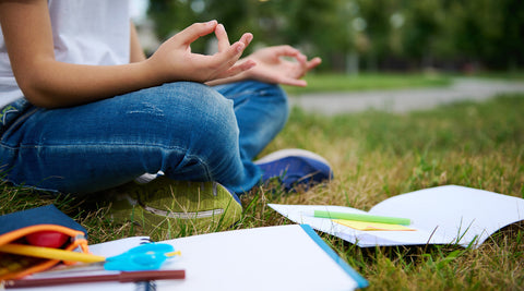 Jovem a meditar num parque para reduzir a ansiedade e melhorar a concentração antes de um teste escolar