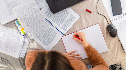Estudante concentrada a estudar para um teste intermédio sentada à secretária em casa 