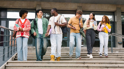 Estudantes universitários com mochilas e material académico no campus da universidade.