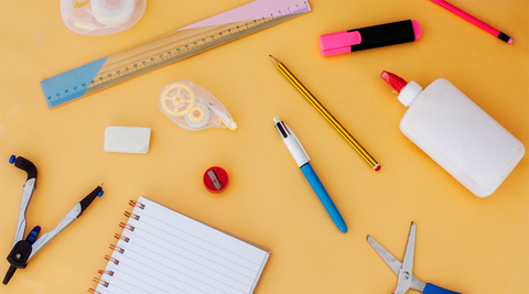 Folha laranja com material escolar espalhado em cima