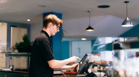 Jovem empregado de café a atender um cliente numa caixa registadora em trabalho part-time para estudantes